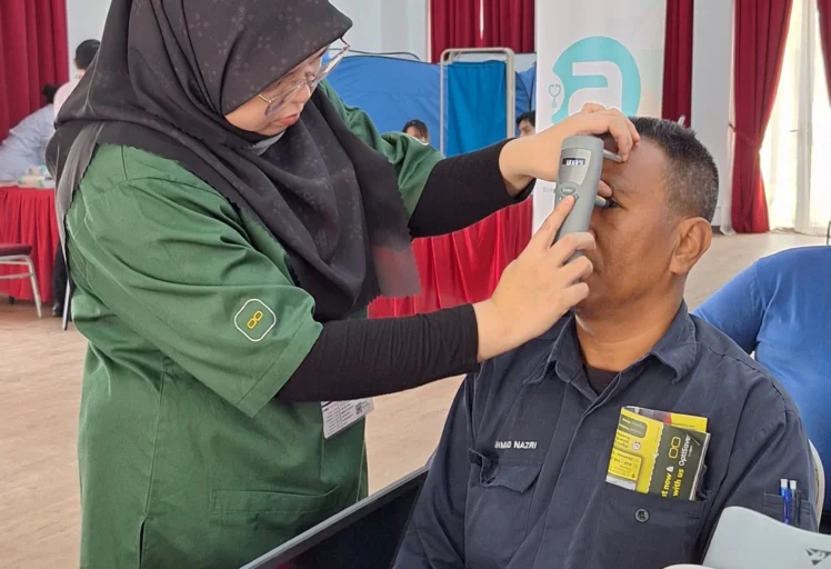 Optometrist conducting dry eye screening test using professional equipment during CSR event.