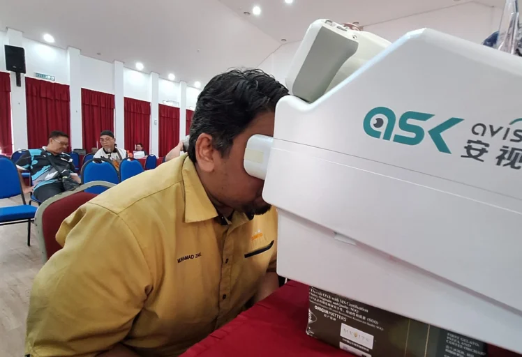 Participant undergoing a retina scan using OptiSaver’s AI-powered diagnostic machine.